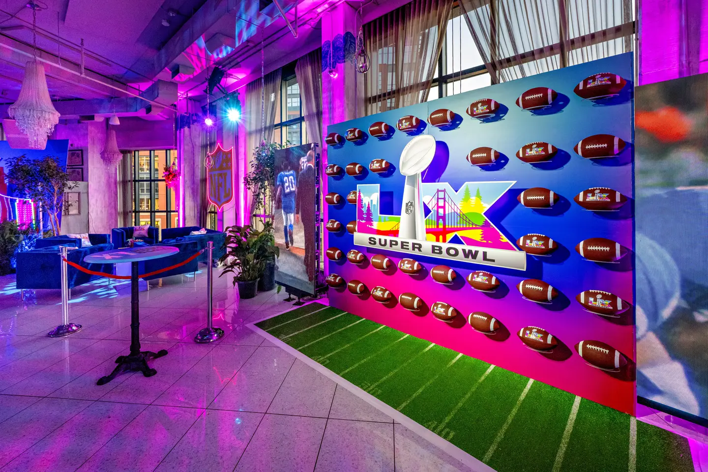 Vibrant Super Bowl-themed room with a colorful mural of the Lombardi Trophy, footballs, and cityscape. Neon lights and lush decor create a lively ambiance
